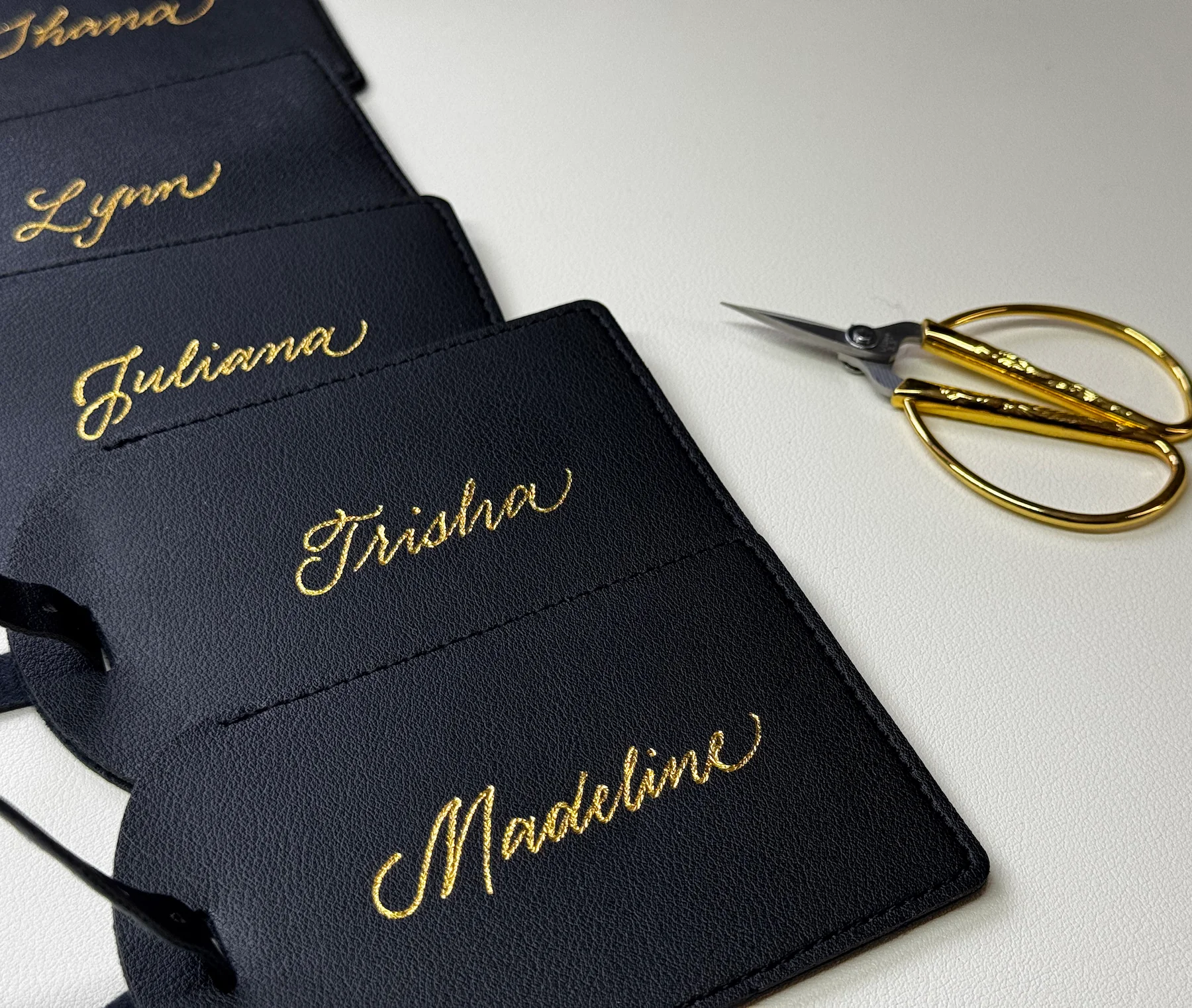 Black luggage tags personalized with gold names